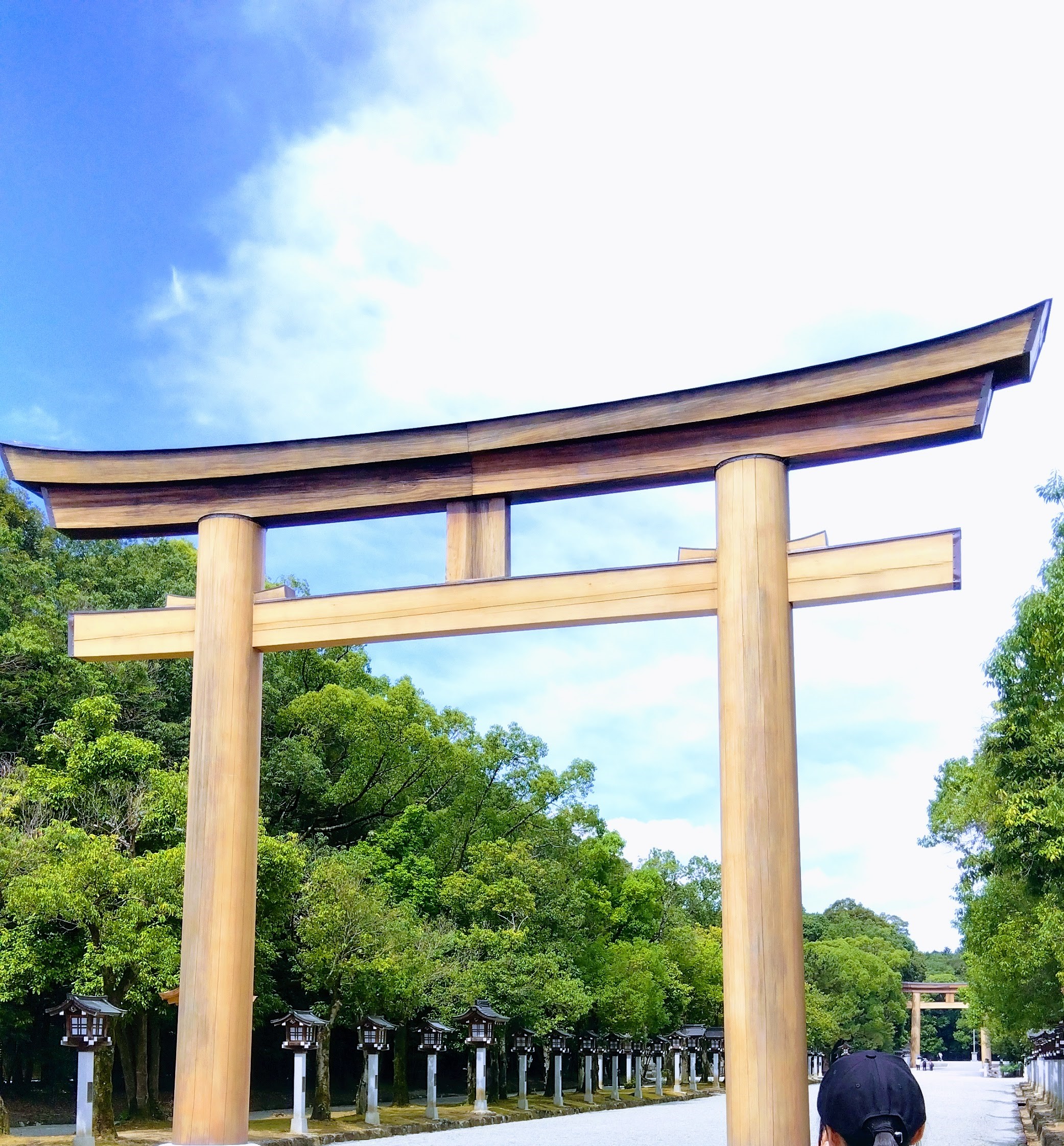 橿原神宮の大鳥居と参道に並ぶ石灯籠。青空が広がる